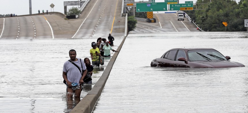 In this Aug. 27, 2017 file photo, evacuees wade down a flooded section of Interstate 610 as floodwaters from Tropical Storm Harvey in Houston. 