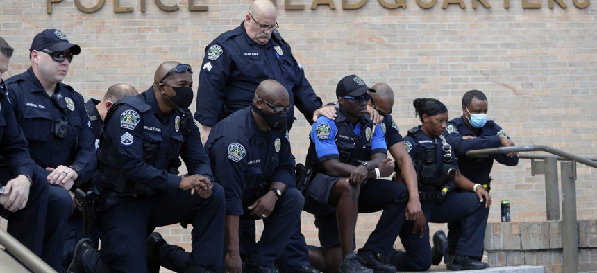 Members of the Austin Police Department kneel in front of demonstrators who gathered in Austin, Texas on June 6, 2020, to protest the death of George Floyd, a black man who was in police custody in Minneapolis. 