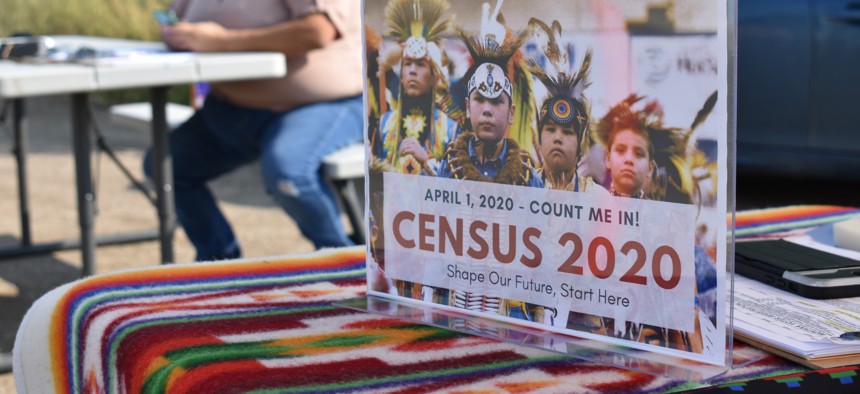 A sign promoting Native American participation in the U.S. census is displayed as Selena Rides Horse enters information into her phone on behalf of a member of the Crow Indian Tribe in Lodge Grass, Mont. on Wednesday, Aug. 26, 2020.