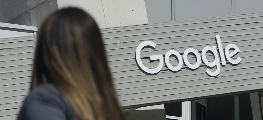 In this Sept. 24, 2019, file photo, a woman walks below a Google sign on the campus in Mountain View, Calif.