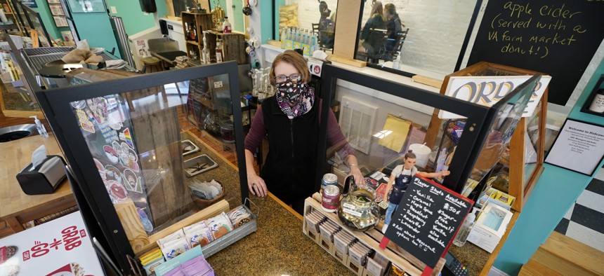Victoria Leigh Kidd, owner of Hideaway Café, greets customers from behind protective shields in her shop in the Old Town area of Winchester, Va., Wednesday, Oct. 7, 2020. 