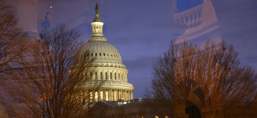 Light illuminates the U.S. Capitol dome as it is seen though window reflections in Washington, Monday, Jan. 27, 2020.