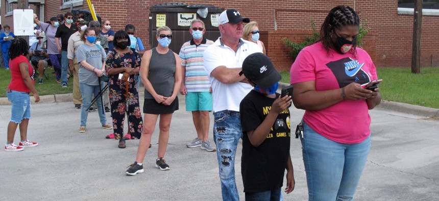 Voters wearing masks wait in line to vote early outside the Chatham County Board of Elections office in Savannah, Ga., on Oct. 14, 2020.