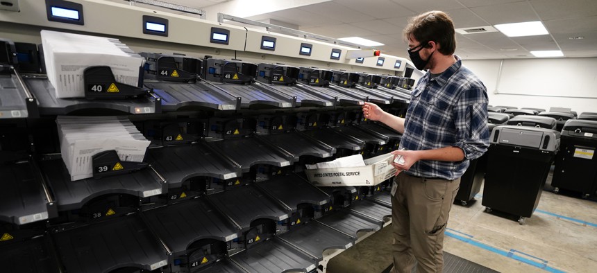 Michael Imms, with Chester County Voter Services, gathers mail-in ballots being sorted for the 2020 General Election in the United States, Friday, Oct. 23, 2020, in West Chester, Pa.