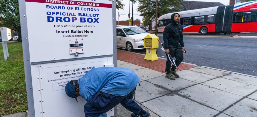 A District of Columbia Board of Election employee locks and seals an official ballot drop box after collecting ballots in northwest Washington, Thursday, Oct. 29, 2020. (AP Photo/Manuel Balce Ceneta)