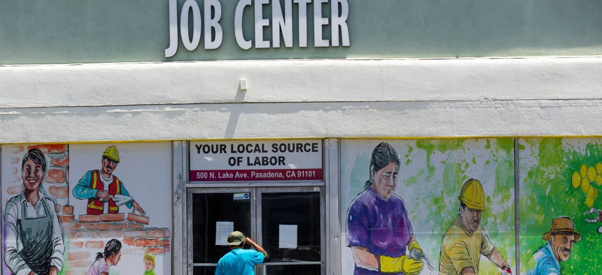 In this May 7, 2020 file photo, a person looks inside the closed doors of the Pasadena Community Job Center in Pasadena, Calif., during the coronavirus outbreak. 