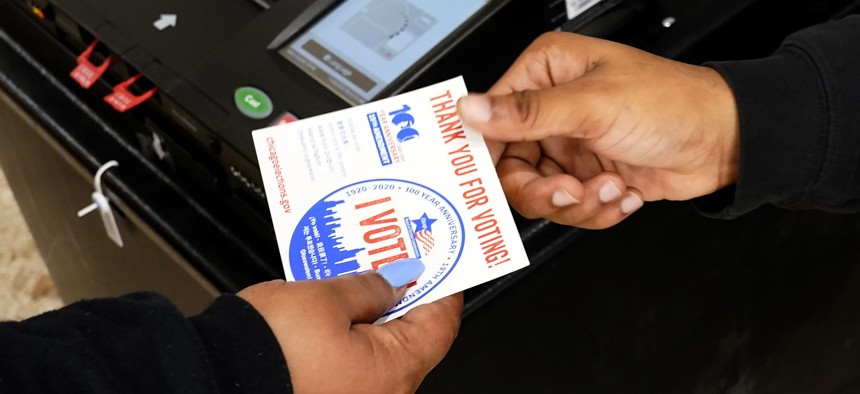 A poll worker hands a voter their "I Voted" sticker on Election Day.