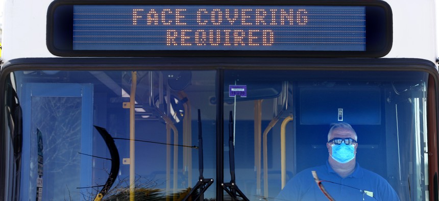 Metro Breez bus driver Rich Price, wearing a face mask, waits at a bus stop on May 13, 2020, in Portland, Maine.