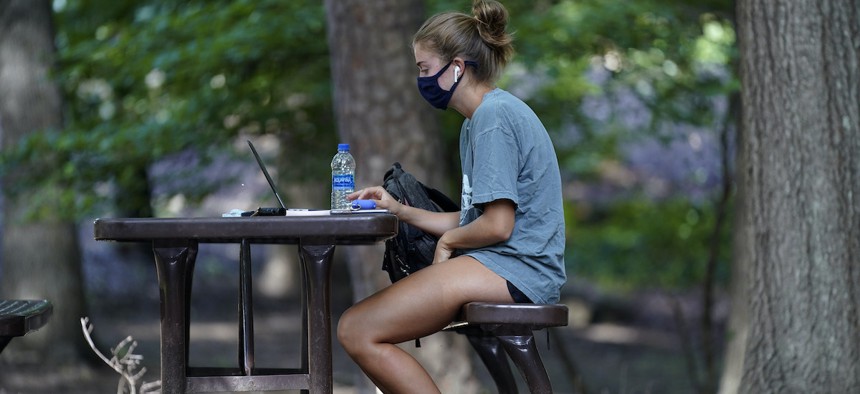 In this Aug. 18, 2020, file photo, a student works outside Ehrighaus dormitory on campus at the University of North Carolina in Chapel Hill, N.C.
