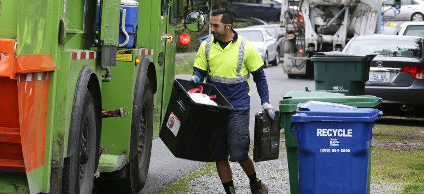David Morales, a garbage driver with Recology, picks up a garbage container for Seattle Public Utilities, Friday, April 15, 2016, in Seattle. 