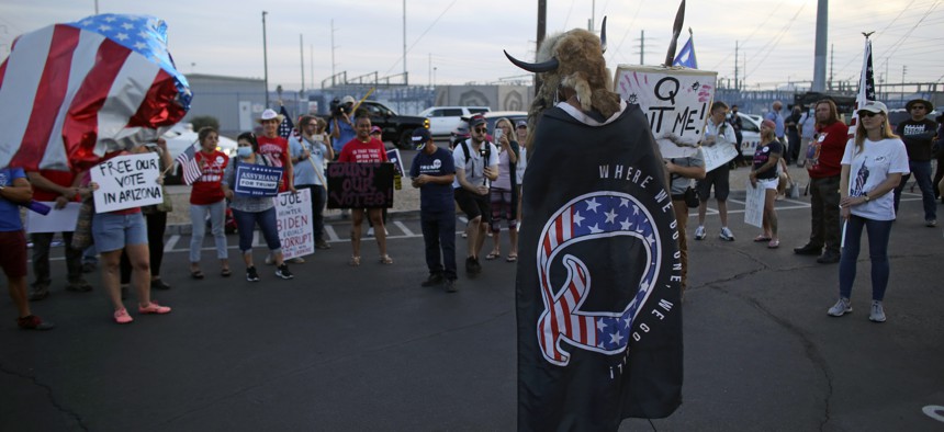 A Qanon believer speaks to a crowd of President Donald Trump supporters outside of the Maricopa County Recorder's Office where votes in the general election are being counted, in Phoenix on Nov. 5, 2020. 