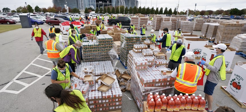 Volunteers build bags of dry goods in a parking lot outside of AT&T Stadium during a Tarrant Area Food Bank mobile pantry distribution event in Arlington, Texas, Friday, Nov. 20, 2020.