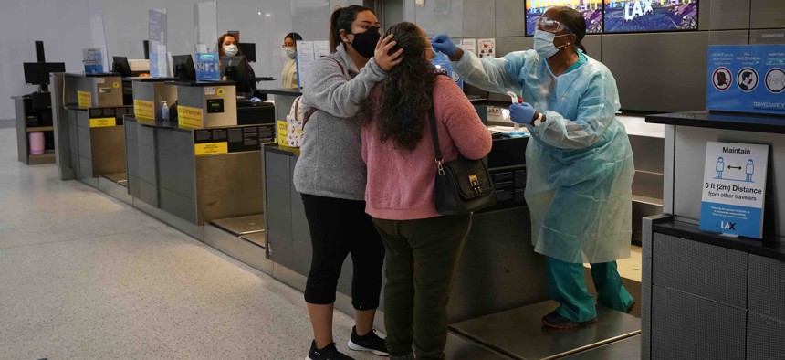 A nurse collects a nasal swab sample from a traveler at a COVID-19 testing site at the Los Angeles International Airport in Los Angeles, Monday, Nov. 23, 2020.