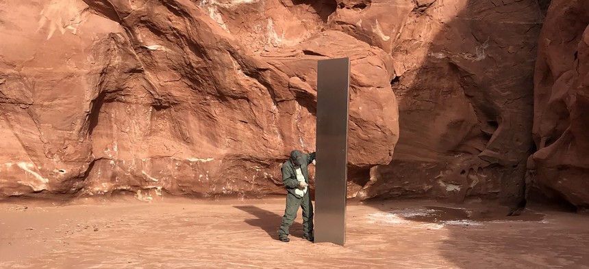 In this Nov. 18, 2020, file photo provided by the Utah Department of Public Safety, a Utah state worker stands next to a metal monolith in the ground in a remote area of red rock in Utah.