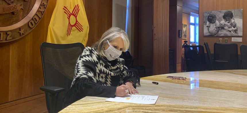 New Mexico Gov. Michelle Lujan Grisham signs a $330 million coronavirus relief package on Nov. 25, 2020.
