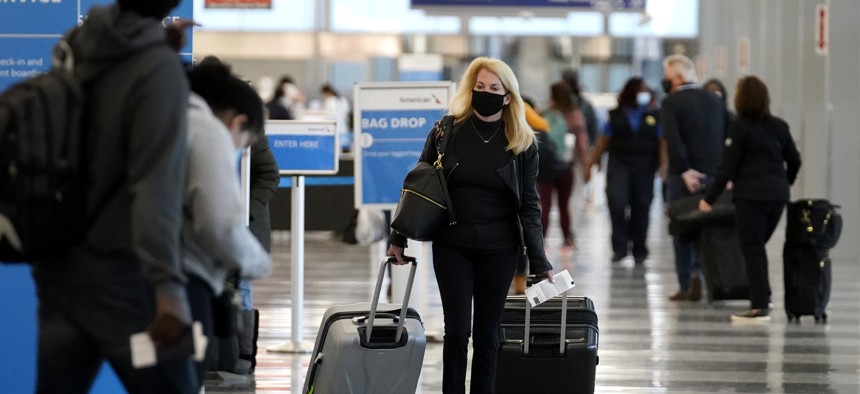 In this Sunday, Nov. 29, 2020 file photo, a traveler wears a mask as she walks through Terminal 3 at O'Hare International Airport in Chicago. 