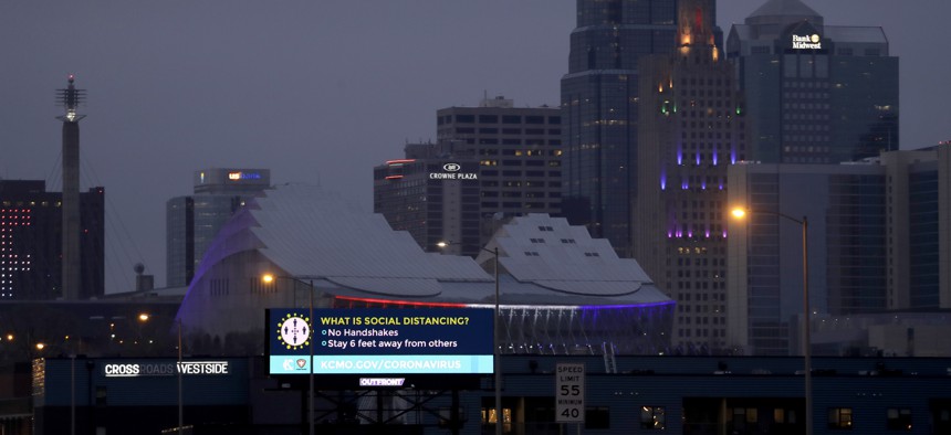 A sign about social distancing stands against the downtown skyline Tuesday, March 24, 2020 on the first day of a stay-at-home order in Kansas City, Mo. 
