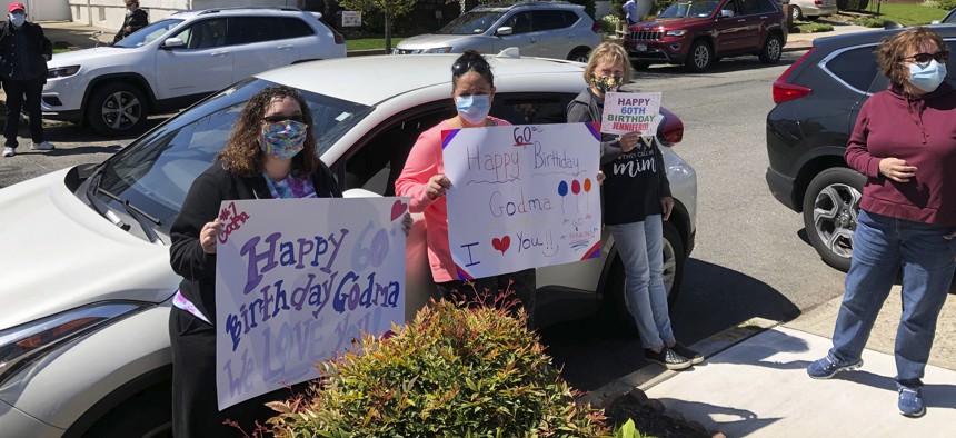 Friends and family have gathered at a social distance to help Jennifer DeSena celebrate her 60th birthday on May 2, 2020, in Long Beach, N.Y., during the coronavirus pandemic. DeSena stood on her front porch for the party.
