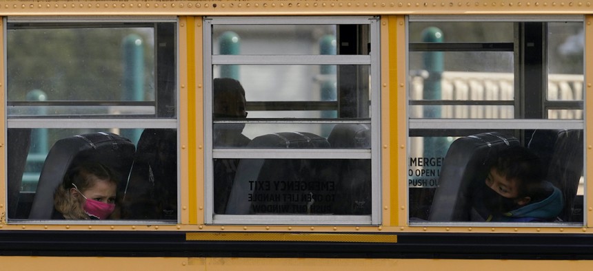 Elementary school students sit on board a school bus after attending in-person classes at school in Wheeling, Ill., Thursday, Nov. 19, 2020.