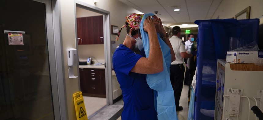 Registered nurse Jana Kendall puts on her PPE before tending to a COVID-19 patient in an emergency room at Mission Hospital in Mission Viejo, Calif. on Dec. 21, 2020.