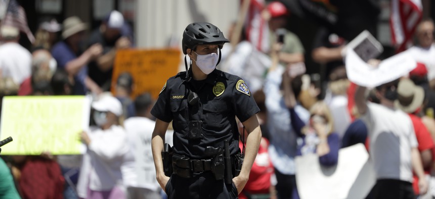 A San Diego police officer looks on during a protest against measures aimed at slowing the spread of the new coronavirus on May 1, 2020, in San Diego, California. 