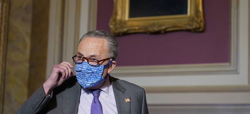 Senate Minority Leader Sen. Chuck Schumer of N.Y., takes off his mask as he arrives to speak to reporters on Capitol Hill in Washington, Wednesday, Dec. 30, 2020.