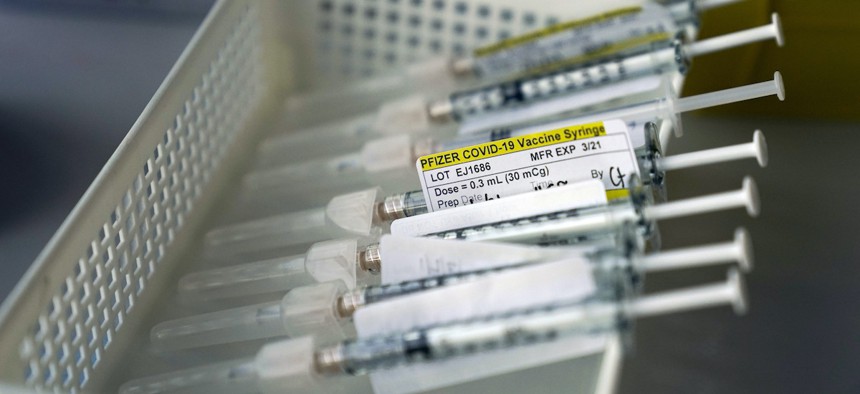 Syringes containing the Pfizer-BioNTech COVID-19 vaccine sit in a tray in a vaccination room at St. Joseph Hospital in Orange, Calif.