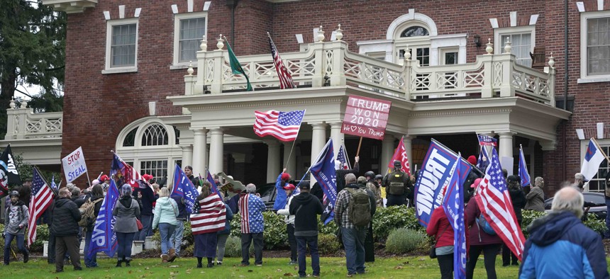 Protesters stand outside the Governor's Mansion after getting through a perimeter fence, Wednesday, Jan. 6, 2021, at the Capitol in Olympia, Wash.