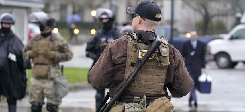 An armed protester stands outside the Capitol Monday, Jan. 11, 2021, in Olympia, Wash. 