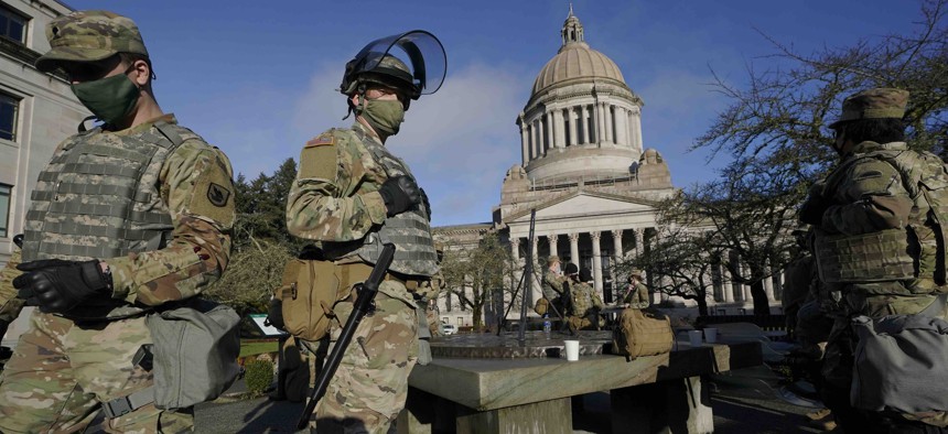 Members of the Washington National Guard stand at a sundial near the Legislative Building, Sunday, Jan. 10, 2021, at the Capitol in Olympia, Wash. 