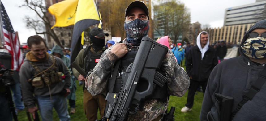 In this April 30, 2020, file photo, a protester carries his rifle at the State Capitol in Lansing, Mich. 