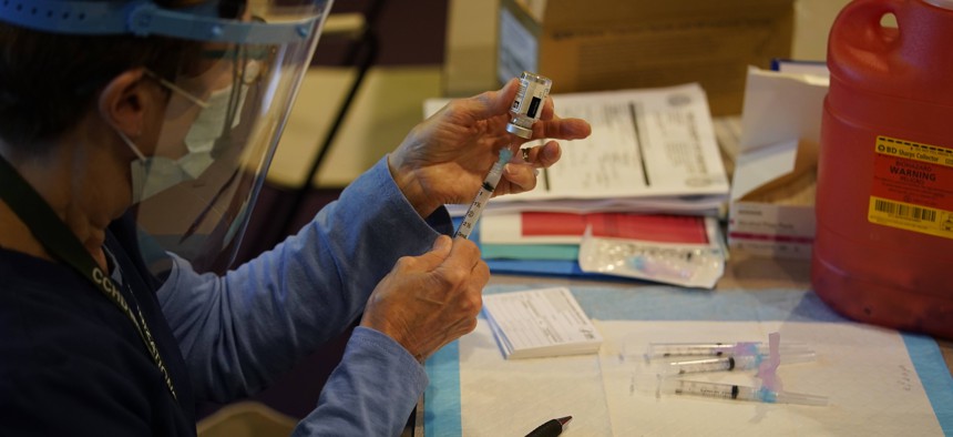 Pat Moore, with the Chester County, Pa., Health Department, fills a syringe with Moderna COVID-19 vaccine before administering it to emergency medical workers and healthcare personnel at the Chester County Government Services Center, Dec. 29, 2020.