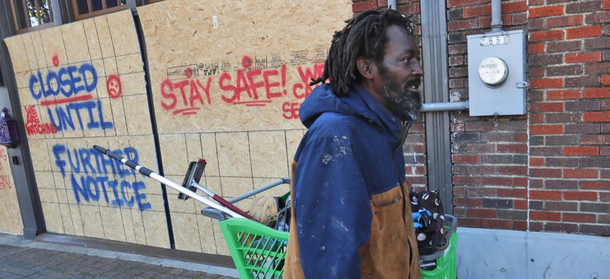 In this Tuesday, March 31, 2020 file photo, Vincent Amos, who identified himself as homeless, pulls a shopping cart with his belongings amid businesses closed by concerns of the COVID-19 coronavirus in the Deep Ellum section of Dallas.