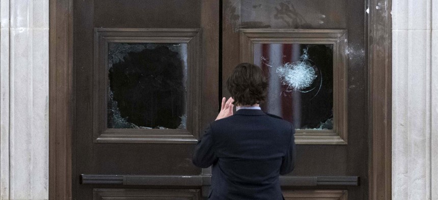 In this Jan. 7, 2021, file photo a man takes a photo of broken windows near the Rotunda in the early morning hours after insurrectionist loyal to President Donald Trump stormed the Capitol in Washington. 