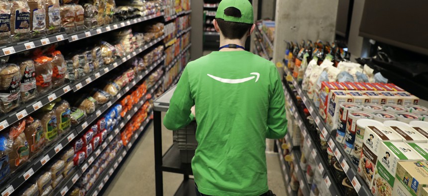 In this Feb. 21, 2020 photo, a worker pushes a cart inside an Amazon Go Grocery store set to open soon in Seattle's Capitol Hill neighborhood. 
