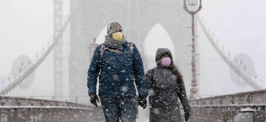 A couple walks on the Brooklyn Bridge, Monday, Feb. 1, 2021 in New York. A winter snowstorm walloped the Eastern U.S. on Monday.