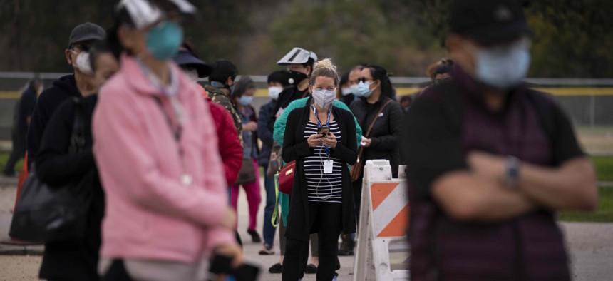 People wait in line to get their COVID-19 vaccine at a vaccination site set up in a park in the Lincoln Heights neighborhood of Los Angeles, Tuesday, Feb. 9, 2021. 