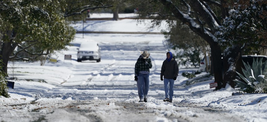 Residents walk through snow, Monday, Feb. 15, 2021, in San Antonio. A winter storm dropping snow and ice also sent temperatures plunging across the southern Plains, prompting a power emergency in Texas.