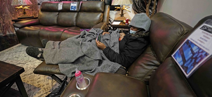 Natalie Harrell holds her sleeping daughter, Natasha Tripeaux while sitting in a recliner at a Gallery Furniture store after the owner opened his business as a shelter for those without power at homes Tuesday, Feb. 16, 2021, in Houston. 