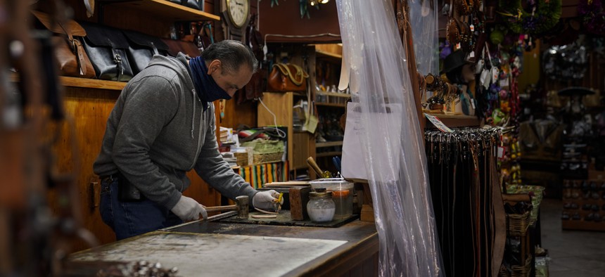 Leather artisan Armando Murillo works in his shop on Olvera Street in downtown Los Angeles, Wednesday, Dec. 16, 2020. Olvera Street, known as the birthplace of Los Angeles, has been particularly hard hit by the coronavirus pandemic.