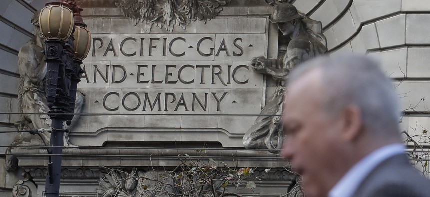 In this Dec. 16, 2019, file photo, is a man walking past a Pacific Gas and Electric sign on a PG&E building in San Francisco.