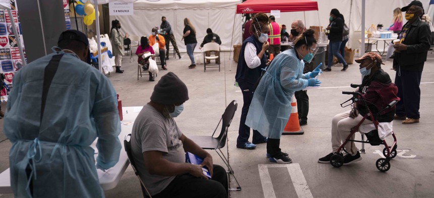 People who are homeless wait to get Covid-19 vaccine shots at a vaccination site set up in the parking lot of the Los Angeles Mission in the Skid Row area of Los Angeles, Wednesday, Feb. 10, 2021.