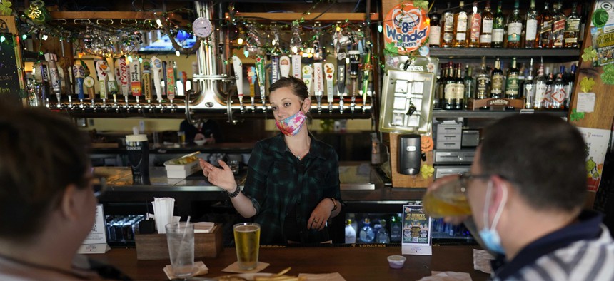 Bartender Alyssa Dooley, center, talks with customers at Mo's Irish Pub, Tuesday, March 2, 2021, in Houston. Texas Gov. Greg Abbott announced that he is lifting business capacity limits and the state's mask mandate starting next week.