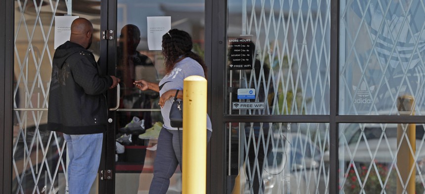 People are unable to enter a business closed due to the coronavirus outbreak Thursday, May 7, 2020, in St. Louis. 