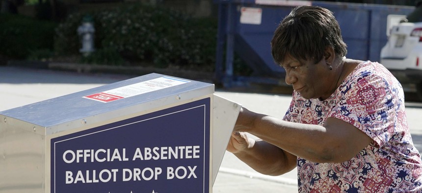 A voter drops their ballot off during early voting in Athens, Ga. 