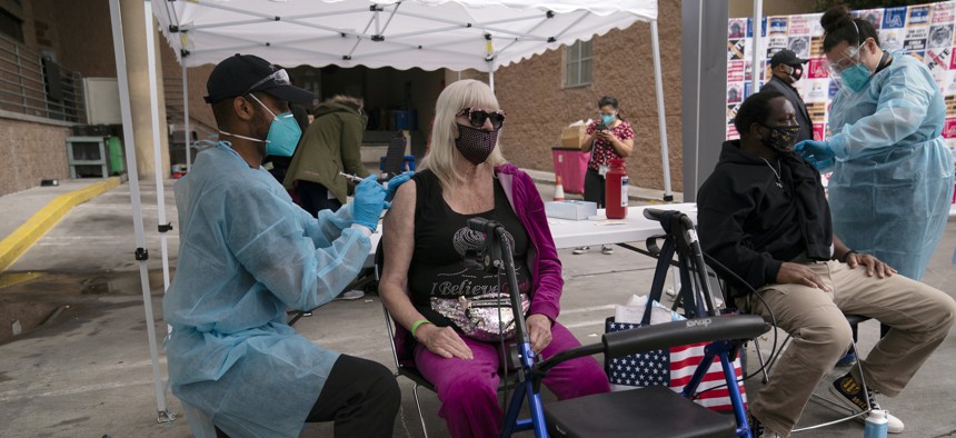 A nurse administers a COVID-19 vaccine to Connie Lach, 66, at a vaccination site set up in the parking lot of the Los Angeles Mission in the Skid Row area of Los Angeles, Wednesday, Feb. 10, 2021.