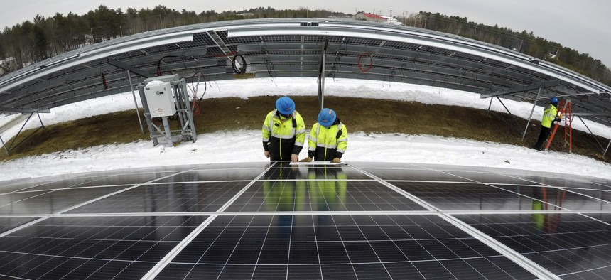 Electricians Bryan Driscoll and Zach Newton and consult a wiring schematic while installing solar panels at the 38-acre BNRG/Dirigo solar farm, Thursday, Jan. 14, 2021, in Oxford, Maine. 