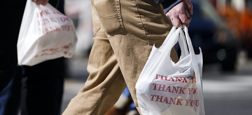 Pedestrians carry plastic bags in Philadelphia, Wednesday, March 3, 2021. Philadelphia and three other municipalities in Pennsylvania sued the state Wednesday over what they say was a covert abuse of legislative power to temporarily halt local bans or tax