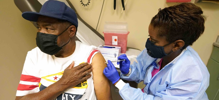 Wilbert Marshall, 71, looks away while receiving a COVID-19 vaccine, from Melissa Banks, right, a nurse at the Aaron E. Henry Community Health Service Center in Clarksdale, Miss., Wednesday, April 7, 2021.