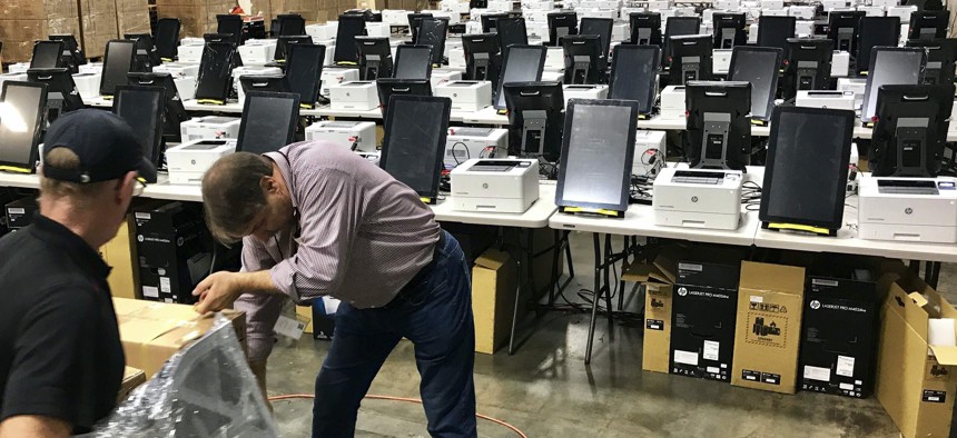 Photo shows voting equipment including touchscreen tablet, printer and scanner in a metro Atlanta warehouse, to be tested before shipped to Georgia counties. With early voting already underway, the Athens-Clarke County Board of Elections voted 3-2.